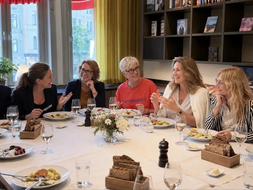 Kvinnor samtalar och skrattar runt ett lunchbord under ett Chair Network-möte